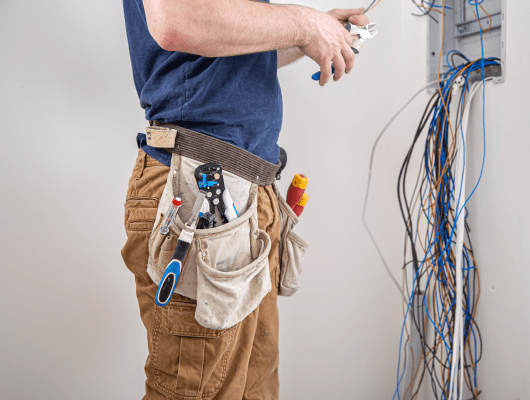 electrician-builder-work-examines-cable-connection-electrical-line-fuselage-industrial-switchboard-professional-overalls-with-electrician-s-tool 1-min