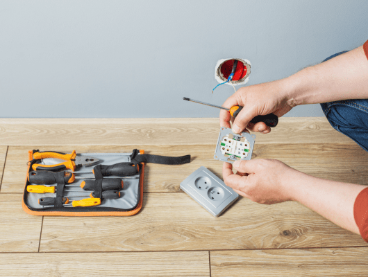 man-installs-electrical-outlet-gray-wall 1-min